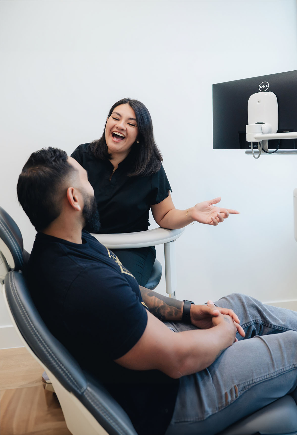 Hygienist laughs with patient in dental chair